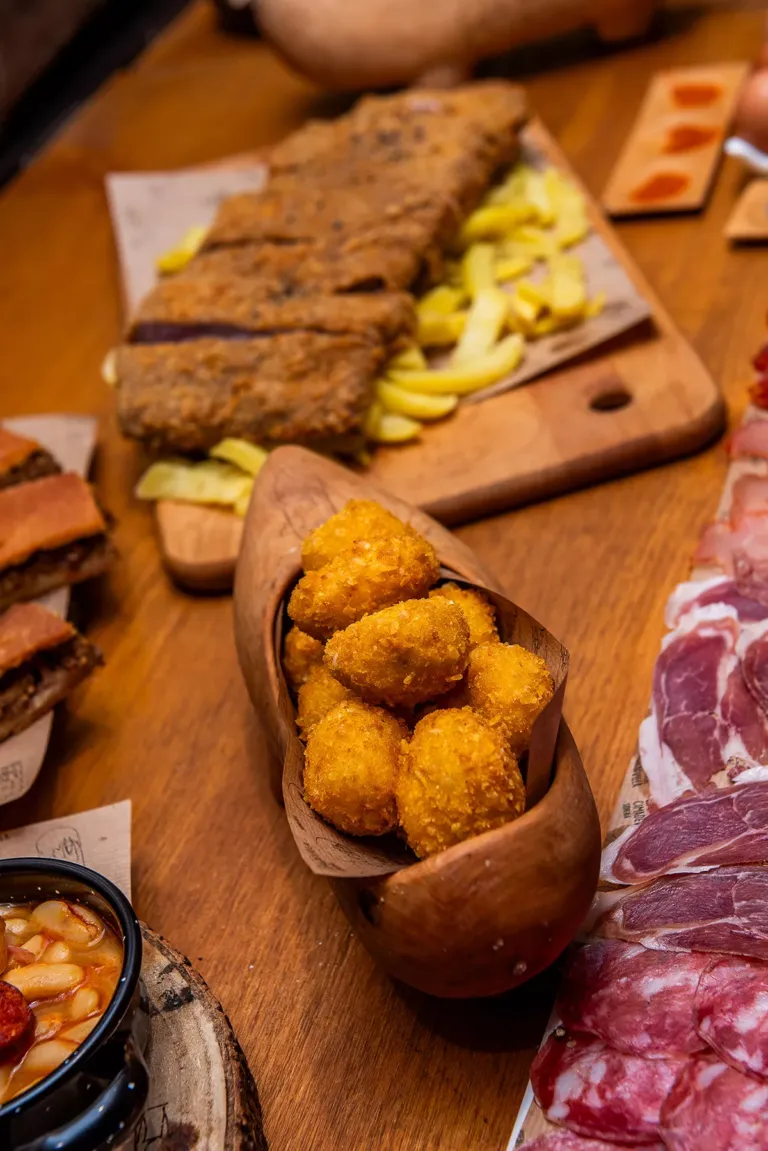 Madreña con croquetas junto a otros platos como croquetas, empanada o embutido