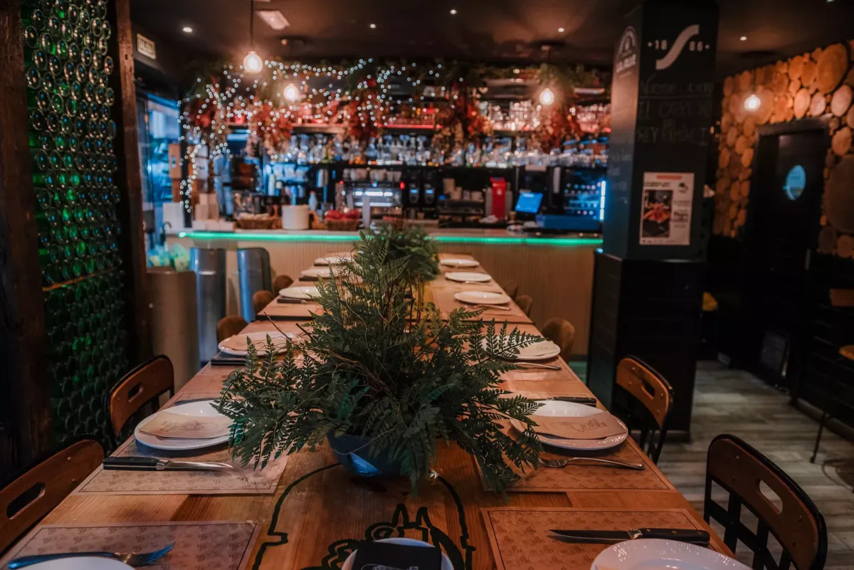 Vista de una mesa larga con la barra del restaurante al fondo